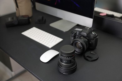 Photo of Professional camera, lens and computer on black desk