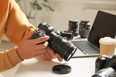 Photo of Photographer with professional camera at white desk indoors, closeup