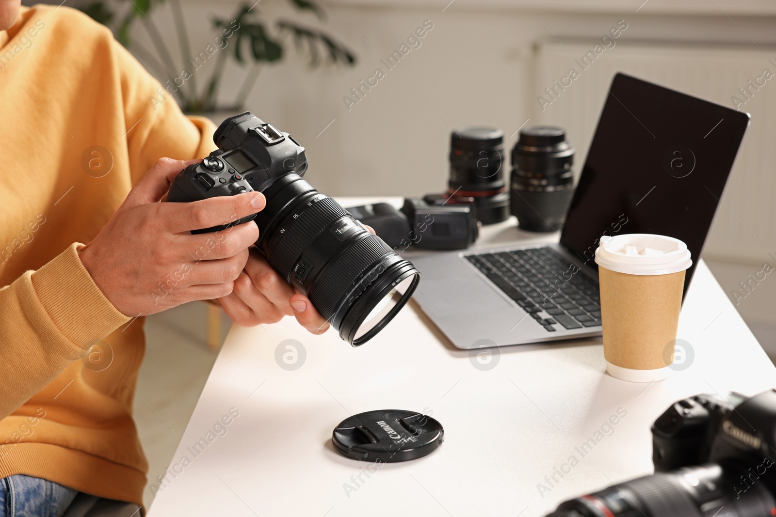 Photo of Photographer with professional camera at white desk indoors, closeup