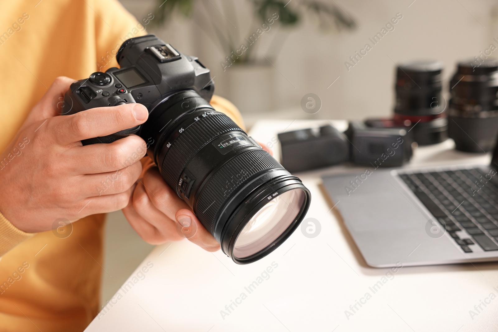 Photo of Photographer with professional camera at white desk indoors, closeup