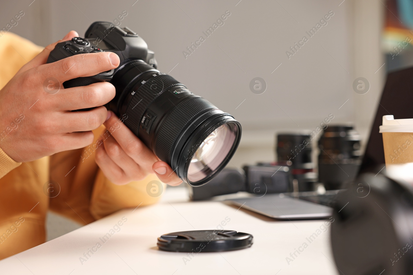 Photo of Photographer with professional camera at white desk indoors, closeup