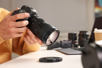 Photo of Photographer with professional camera at white desk indoors, closeup