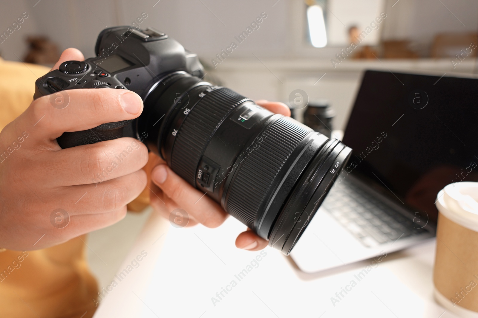 Photo of Photographer with professional camera at white desk indoors, closeup