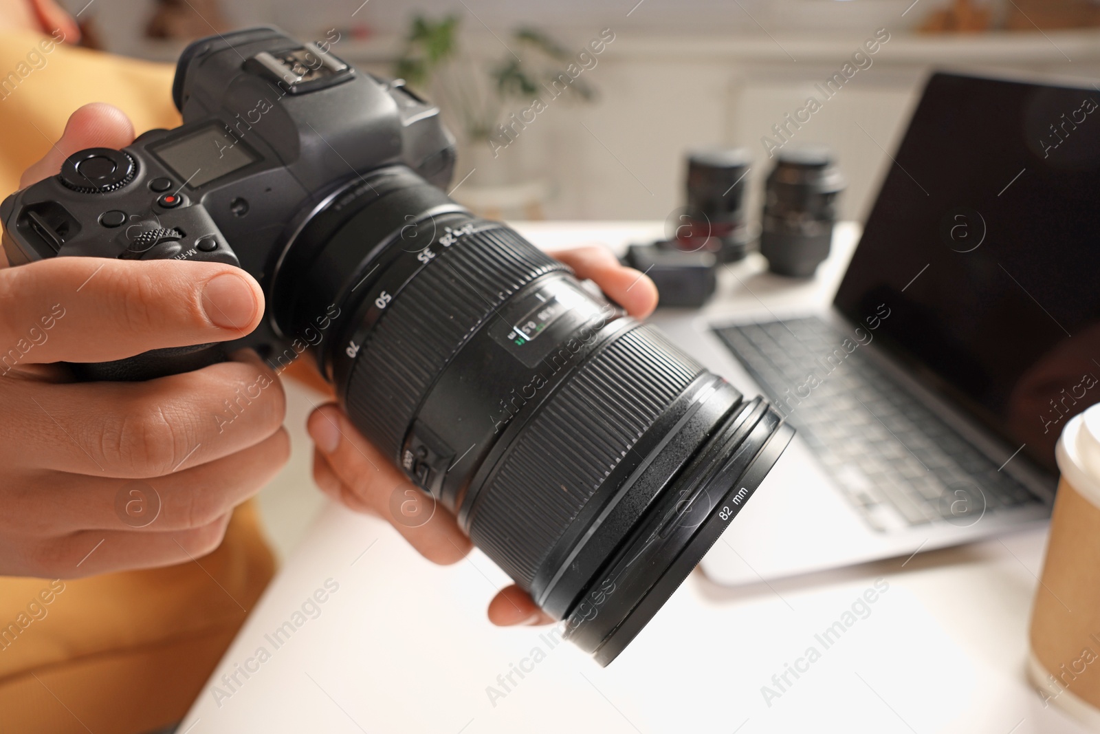 Photo of Photographer with professional camera at white desk indoors, closeup