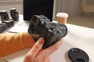 Photo of Photographer with professional camera at white desk indoors, closeup