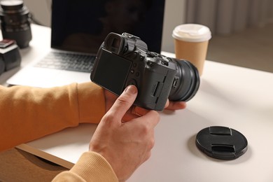 Photo of Photographer with professional camera at white desk indoors, closeup