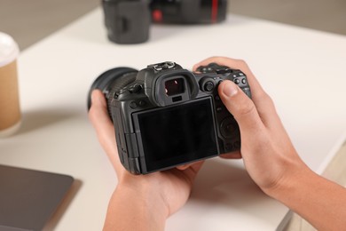 Photo of Photographer with professional camera at white desk indoors, closeup