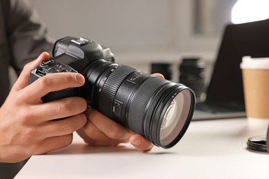 Photo of Photographer with professional camera at white desk indoors, closeup