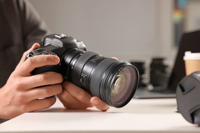 Photo of Photographer with professional camera at white desk indoors, closeup