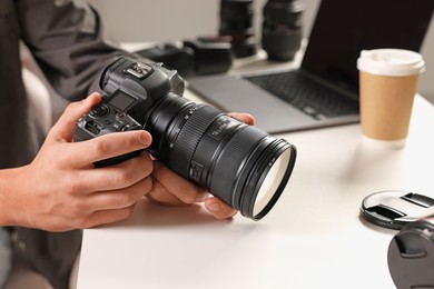 Photo of Photographer with professional camera at white desk indoors, closeup