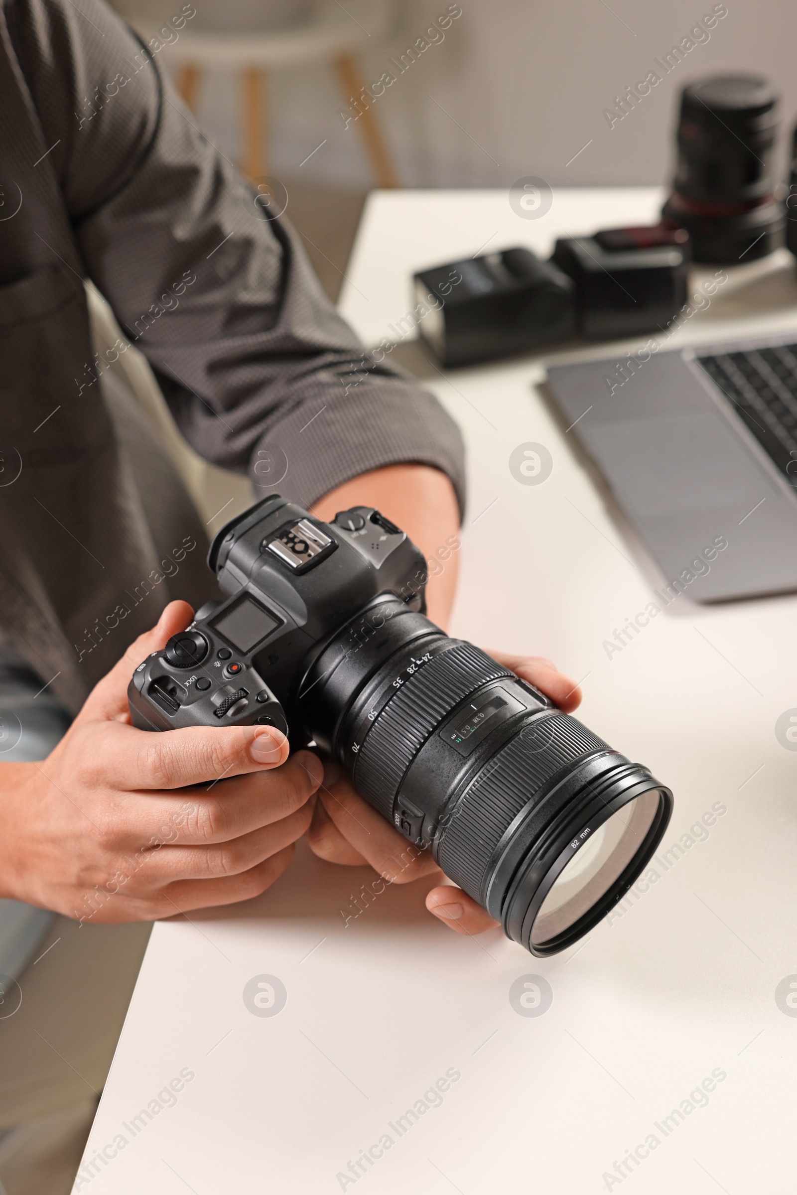 Photo of Photographer with professional camera at white desk indoors, closeup