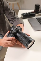 Photo of Photographer with professional camera at white desk indoors, closeup