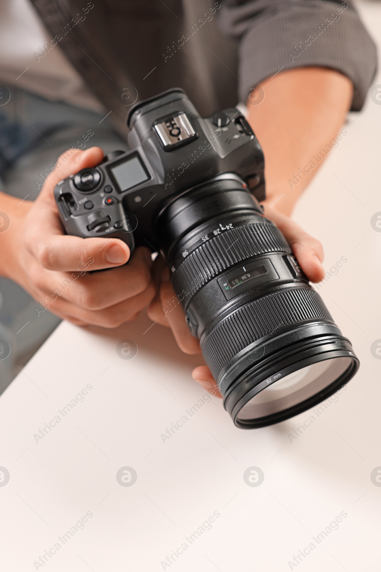 Photo of Photographer with professional camera at white desk indoors, closeup