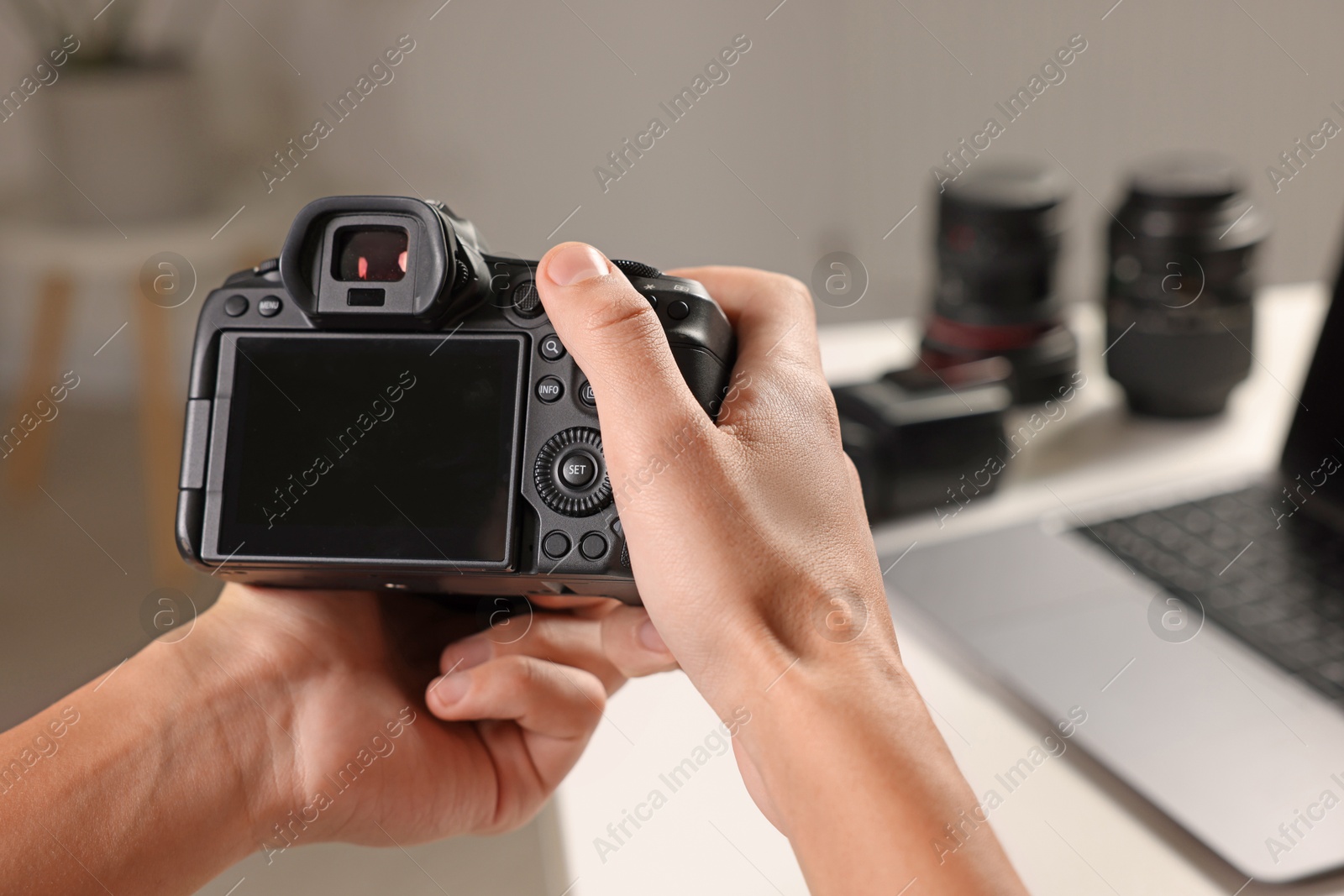 Photo of Photographer with professional camera at white desk indoors, closeup