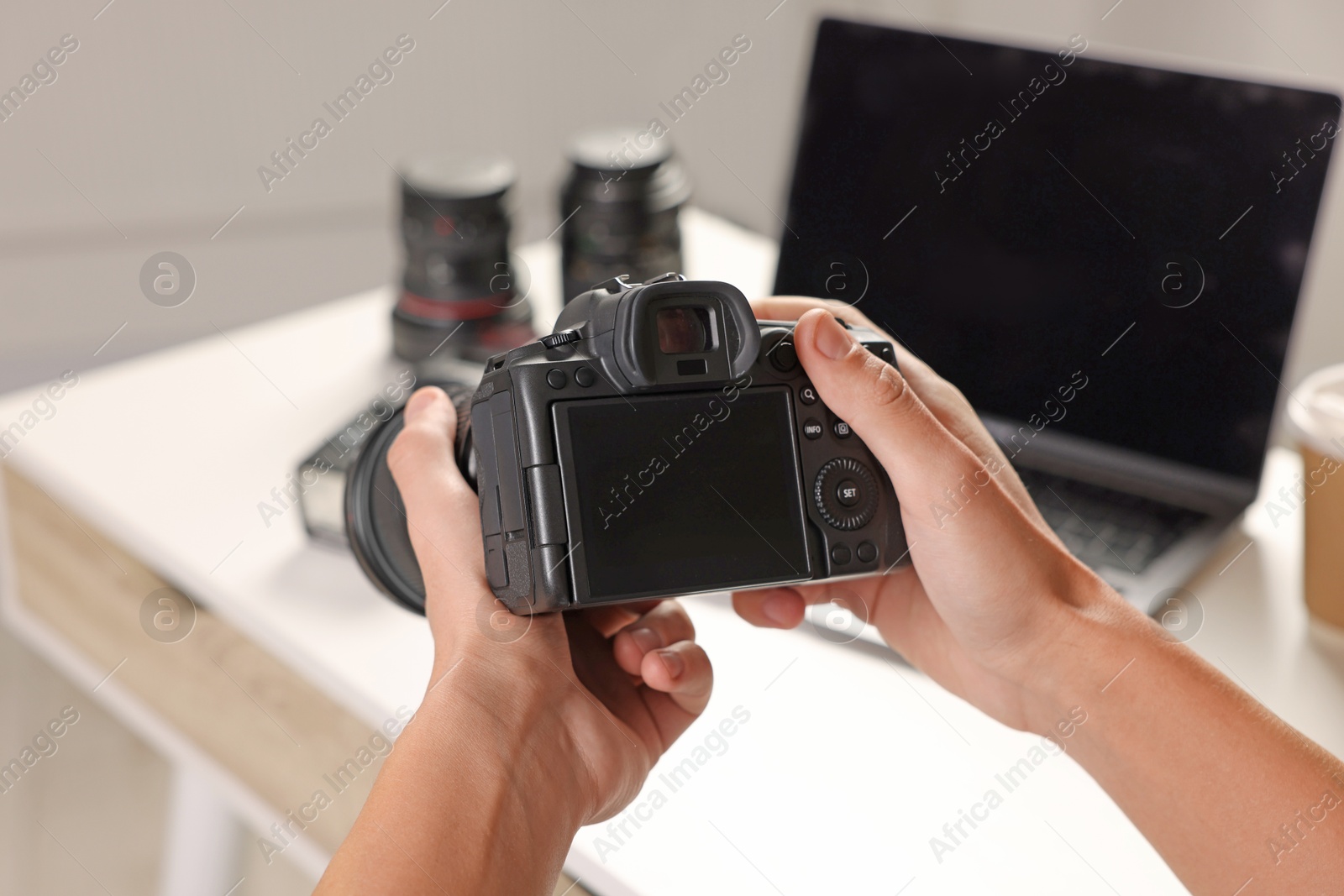 Photo of Photographer with professional camera at white desk indoors, closeup