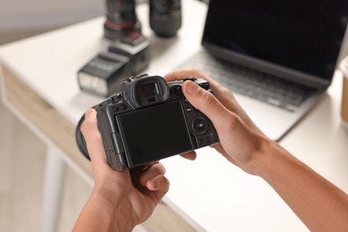 Photo of Photographer with professional camera at white desk indoors, closeup