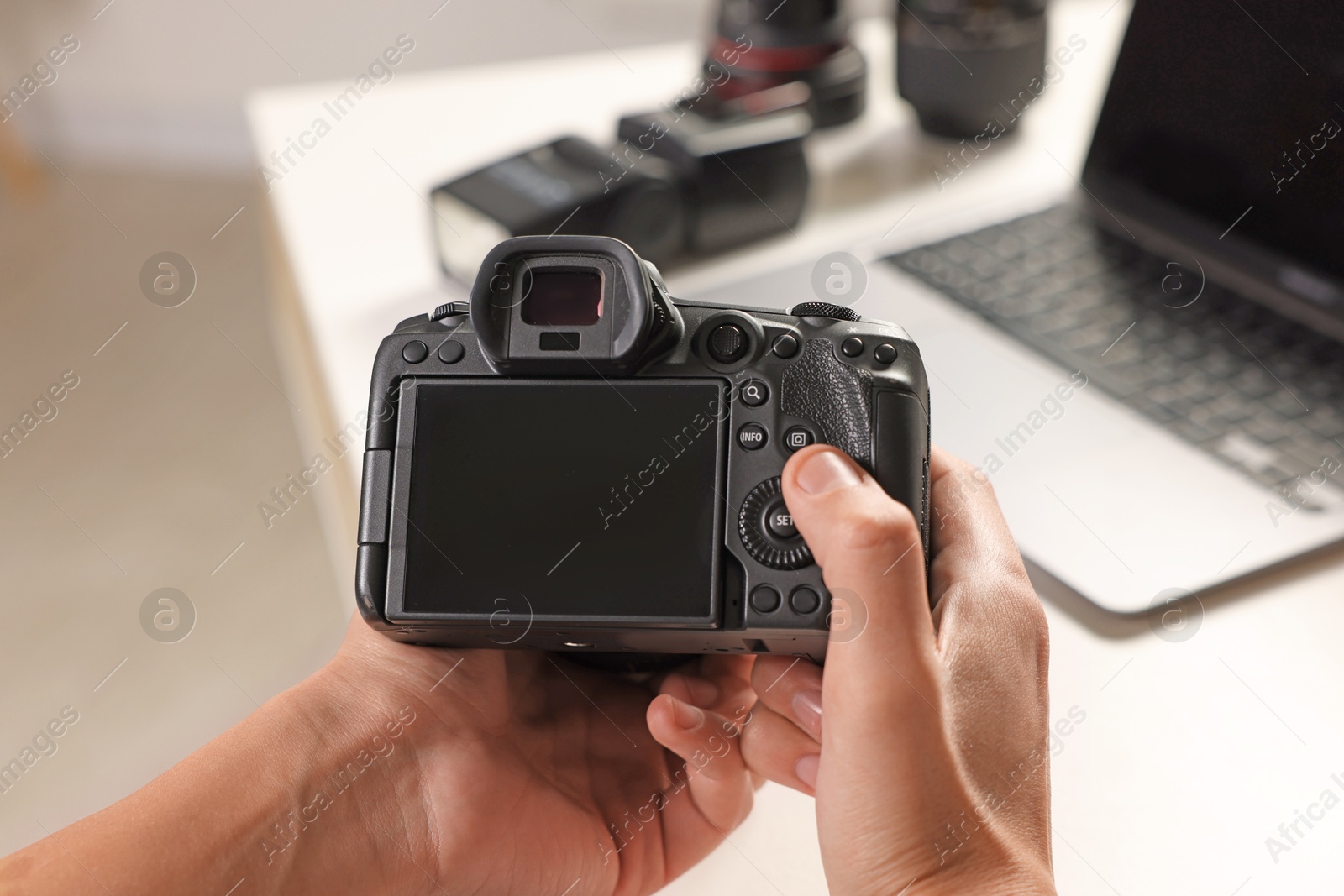 Photo of Photographer with professional camera at white desk indoors, closeup