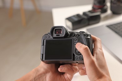 Photo of Photographer with professional camera at white desk indoors, closeup