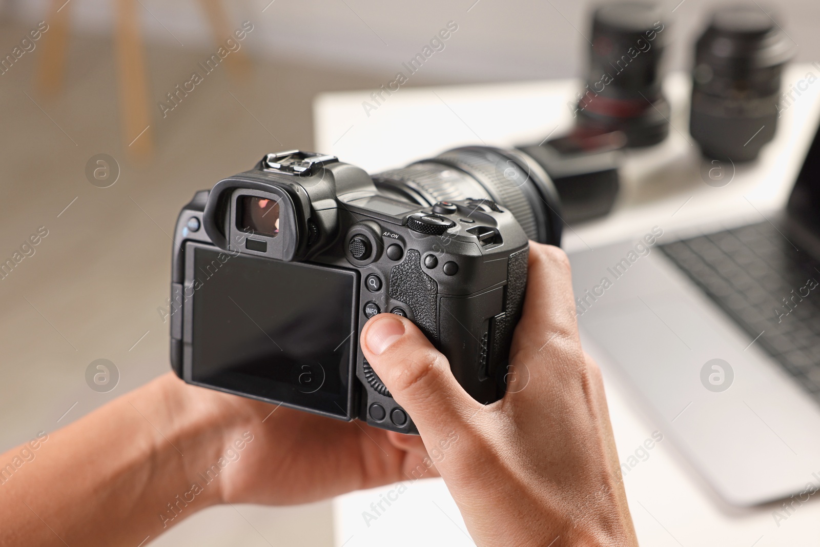 Photo of Photographer with professional camera at white desk indoors, closeup