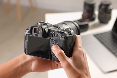 Photo of Photographer with professional camera at white desk indoors, closeup