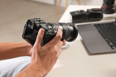 Photo of Photographer with professional camera at white desk indoors, closeup