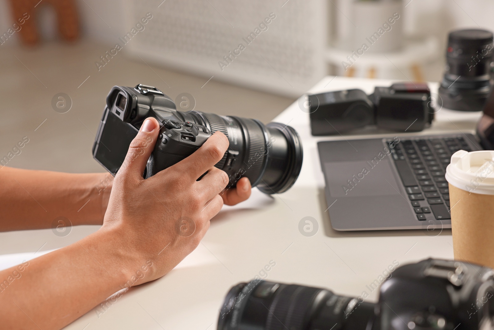 Photo of Photographer with professional camera at white desk indoors, closeup