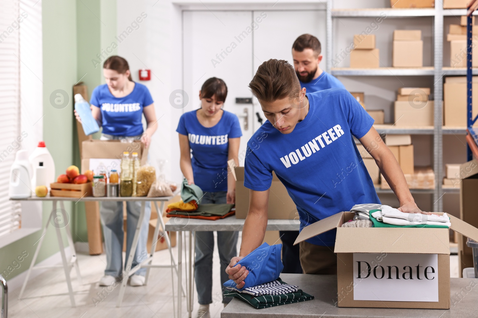 Photo of Group of volunteers packing donation goods at tables indoors