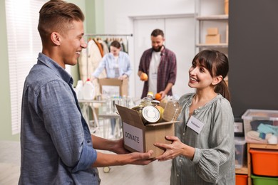 Volunteers holding donation box with food products indoors, selective focus