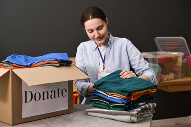 Photo of Volunteer sorting clothes for donation at table indoors