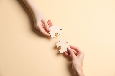 Photo of Business strategy and teamwork concept. Partners putting puzzle pieces together on beige background, top view