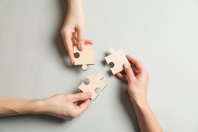 Photo of Business strategy and teamwork concept. Partners with different puzzle pieces on grey background, top view