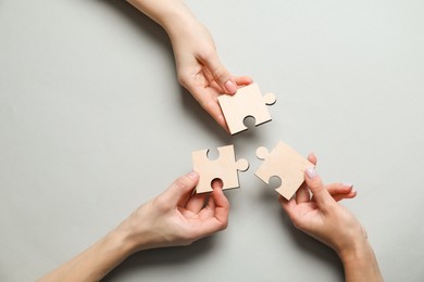 Photo of Business strategy and teamwork concept. Partners with different puzzle pieces on grey background, top view