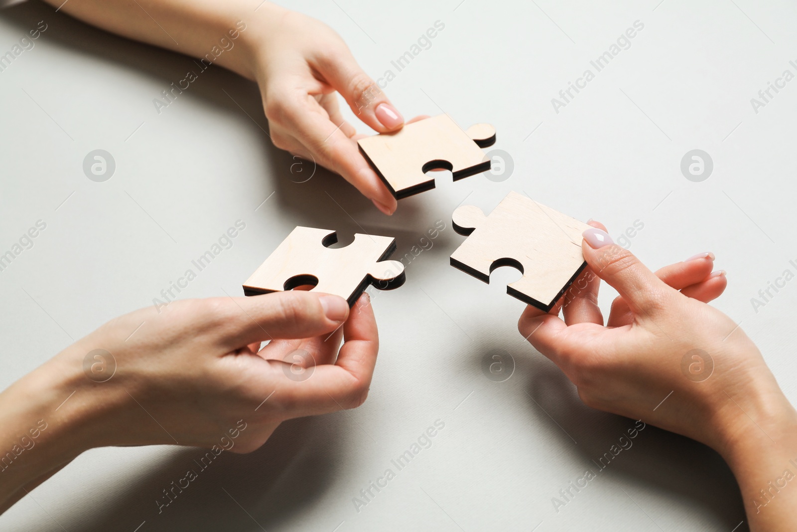 Photo of Business strategy and teamwork concept. Partners with different puzzle pieces on grey background, closeup