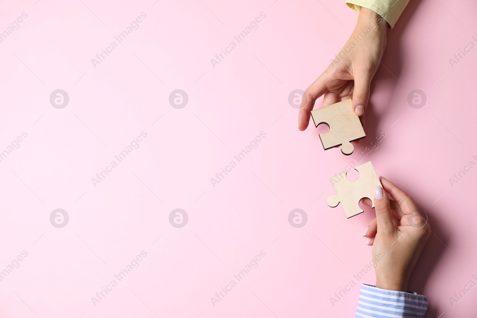 Photo of Business strategy and teamwork concept. Partners putting puzzle pieces together on pink background, top view with space for text