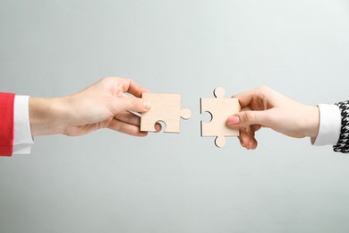 Photo of Business strategy and teamwork concept. Partners putting puzzle pieces together on grey background, closeup