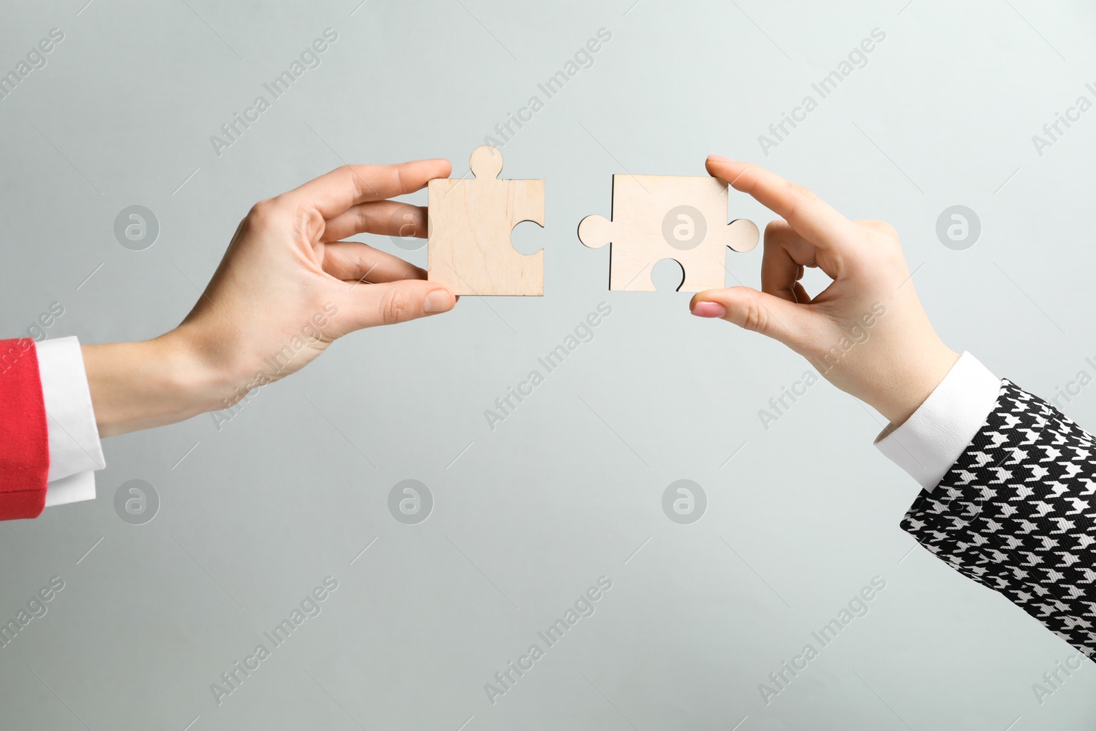 Photo of Business strategy and teamwork concept. Partners putting puzzle pieces together on grey background, closeup