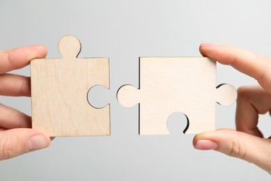 Photo of Business strategy and teamwork concept. Partners putting puzzle pieces together on grey background, closeup