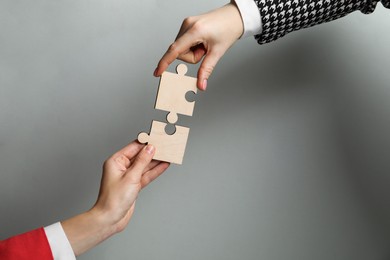 Photo of Business strategy and teamwork concept. Partners putting puzzle pieces together on grey background, closeup