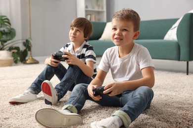 Photo of Cute brothers playing video game on floor at home