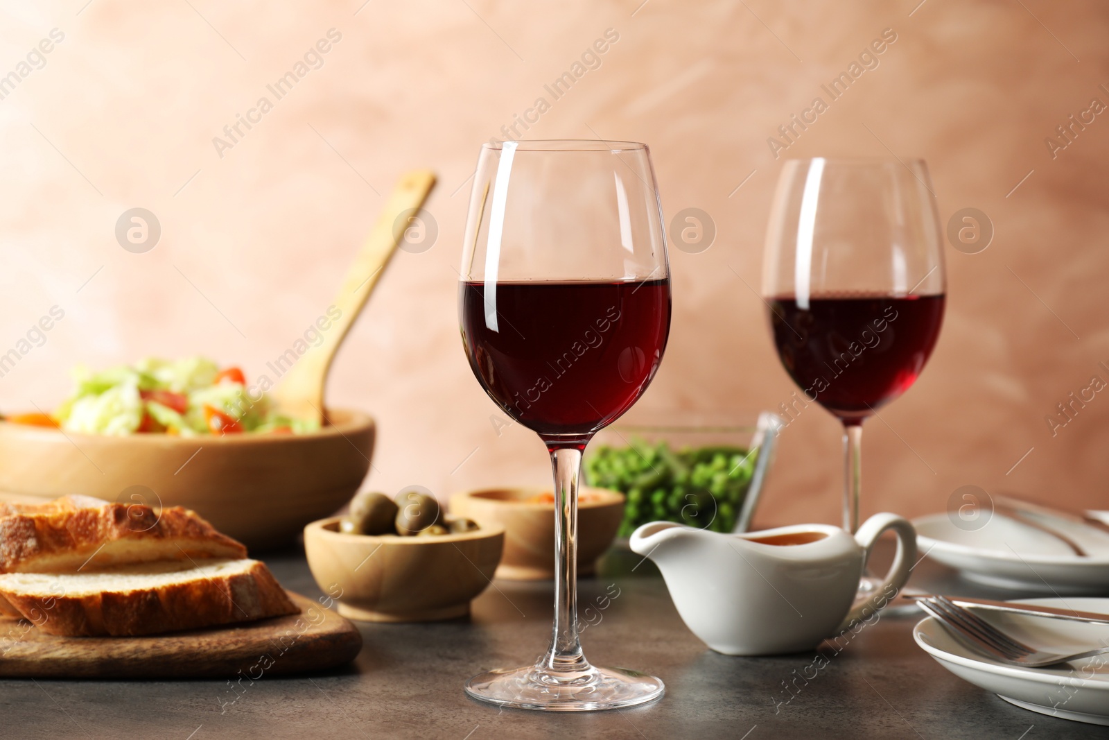 Photo of Red wine and delicious dinner served on grey table