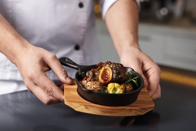 Photo of Professional chef serving dish at table indoors, closeup