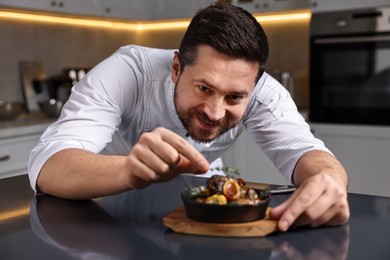 Photo of Professional chef serving dish at table indoors