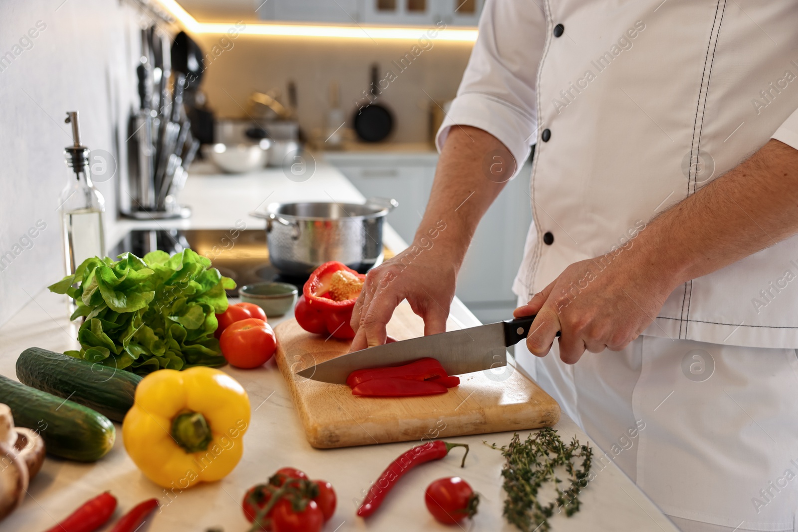 Photo of Professional chef cutting bell pepper at counter in kitchen, closeup