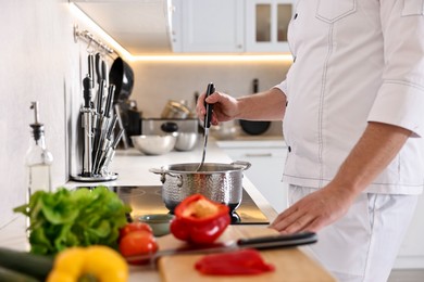 Photo of Professional chef cooking meal at stove in kitchen, closeup