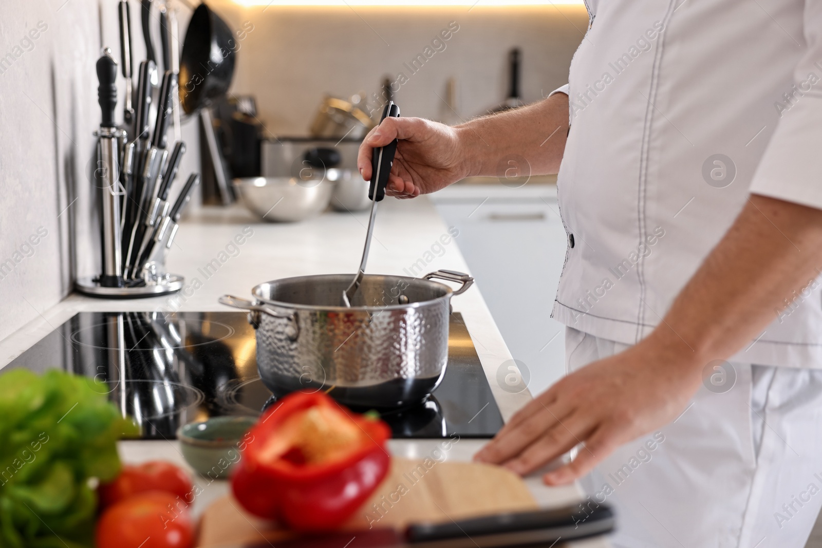 Photo of Professional chef cooking meal at stove in kitchen, closeup