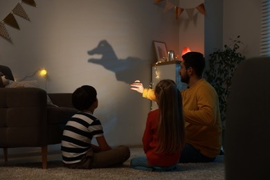 Photo of Man making hand gesture like goose while performing shadow play to his kids at home