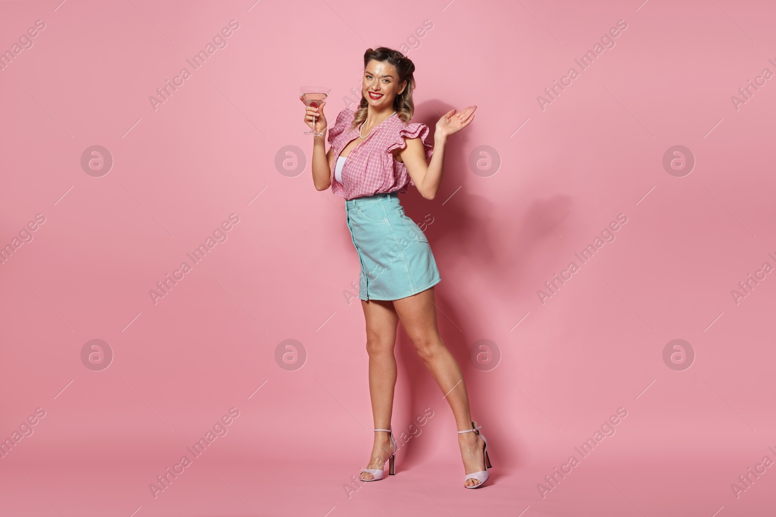 Photo of Happy pin-up woman with cocktail on pink background