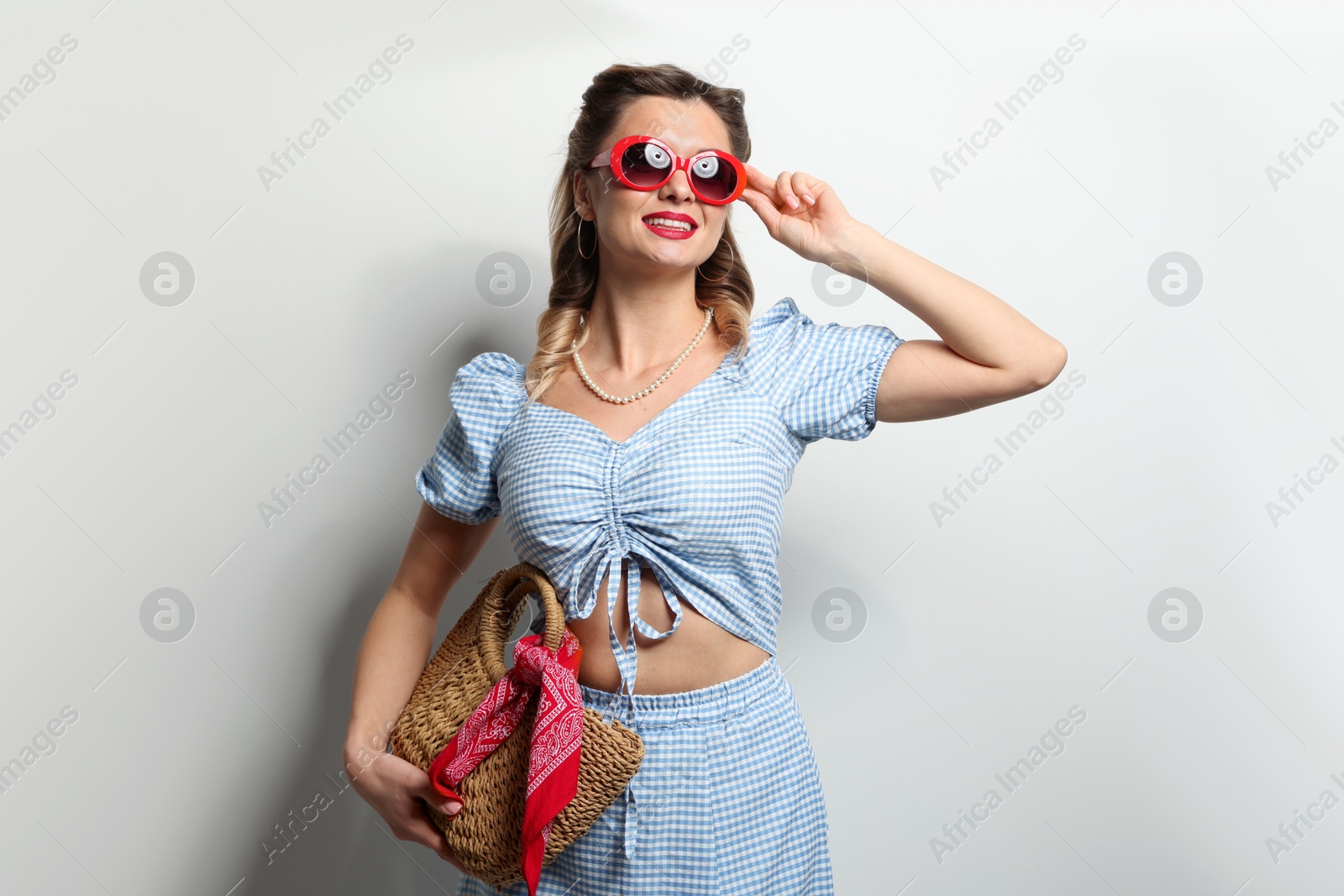 Photo of Happy pin-up woman in sunglasses on light background