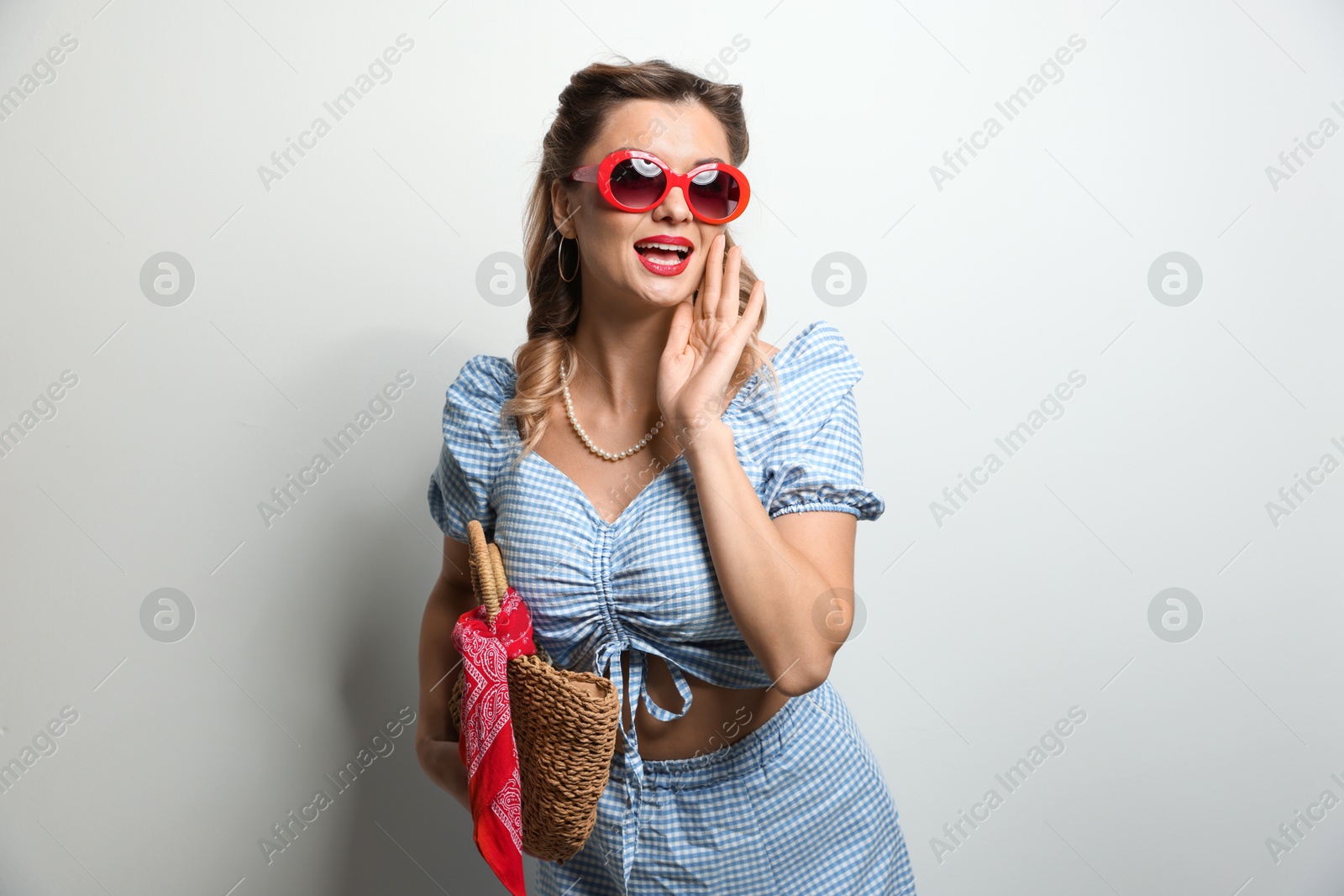 Photo of Happy pin-up woman in sunglasses on light background