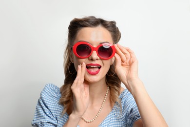 Photo of Portrait of happy pin-up woman in sunglasses on light background